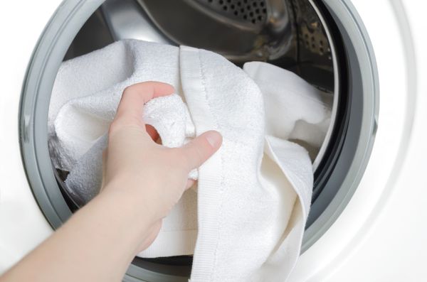 A person pulling a towel from a front load washer